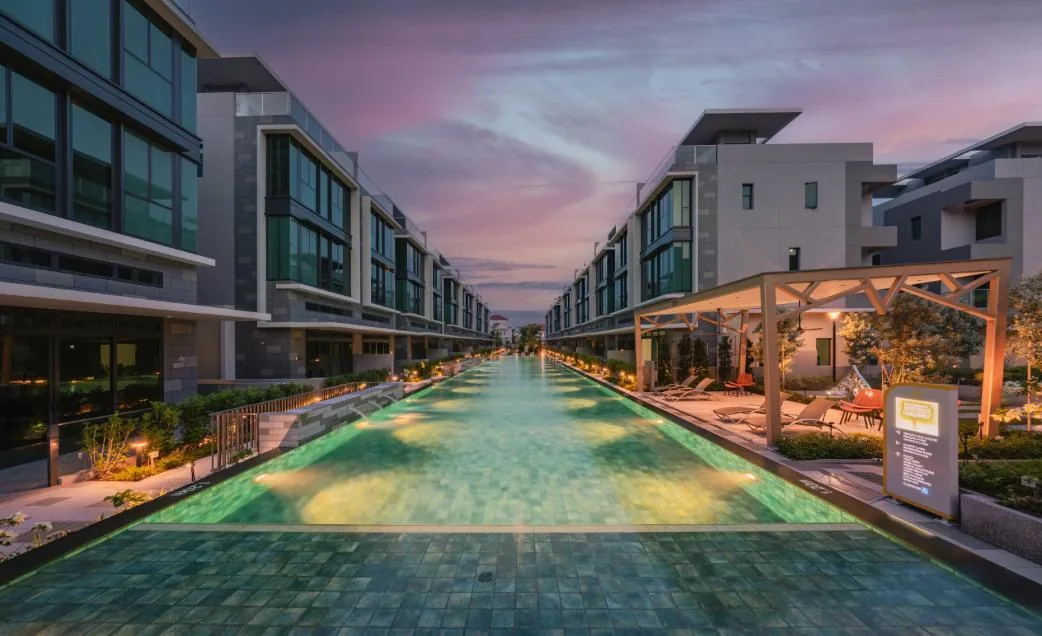 Belgravia Ace 50m lap pool illuminated at dusk between the house rows